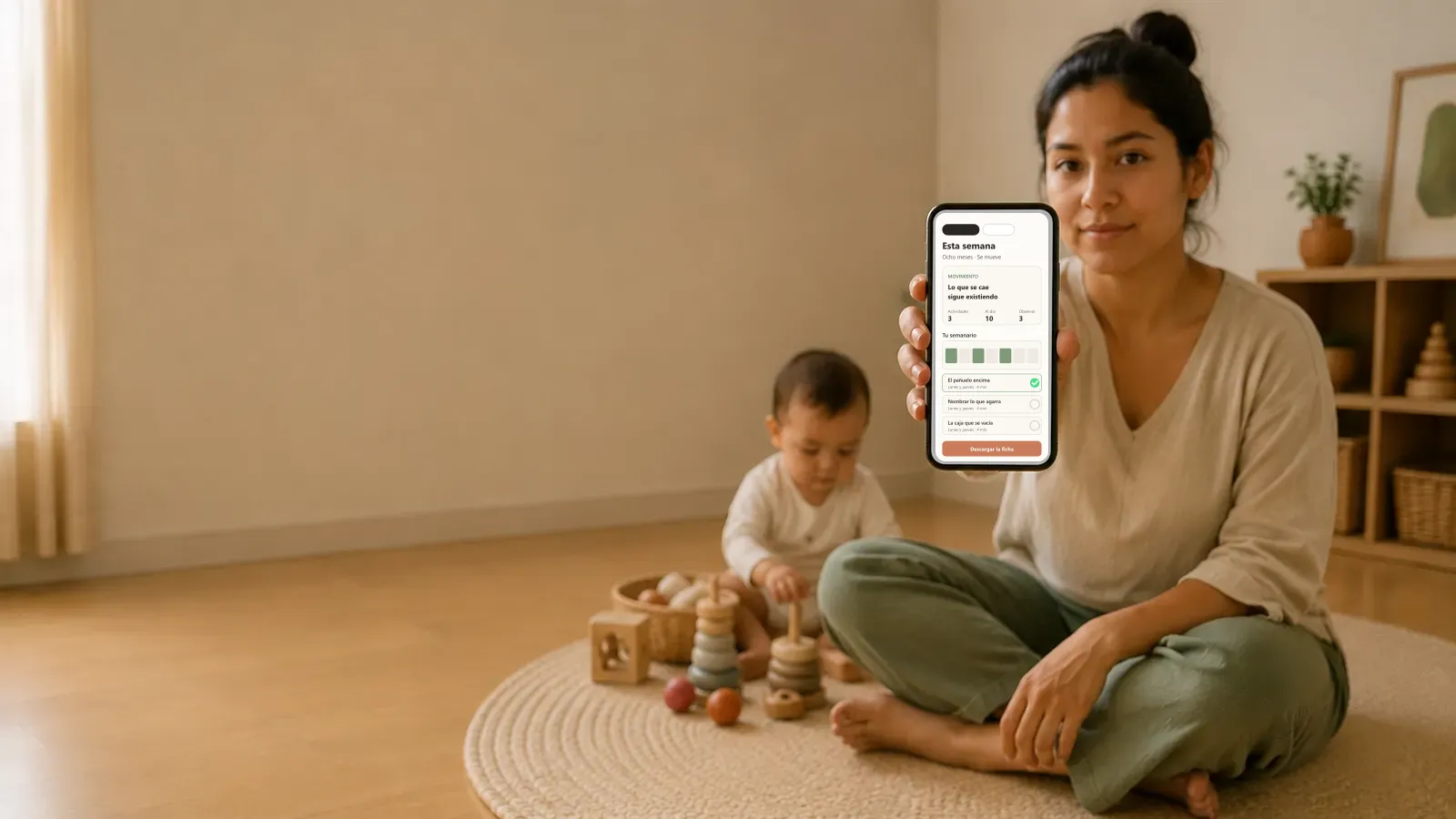 Una madre en el suelo con su bebé, enseñando en el teléfono la semana que le toca